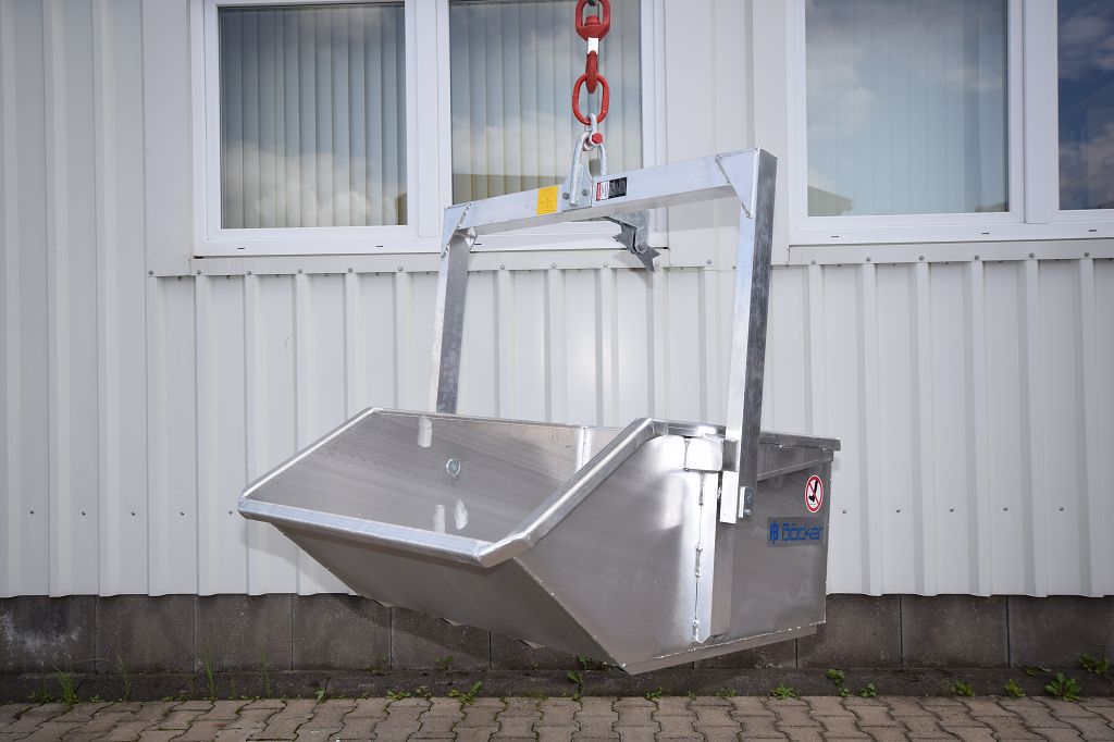 Bild silbernfarbene Schuttmulde klein. Im Hintergrund ein weißes Gebäude