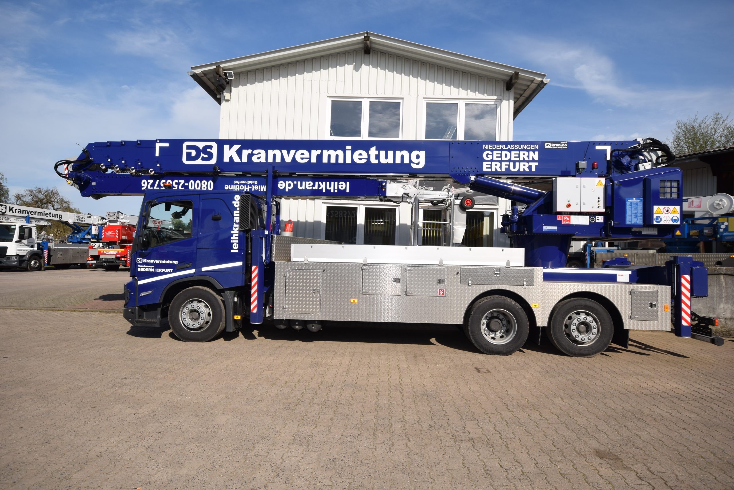 Klaas RSX 60m Bild Klaas RSX 60m vor einem weißem Gebäude im Hintergrund sind noch zwei Autokrane zu sehen.