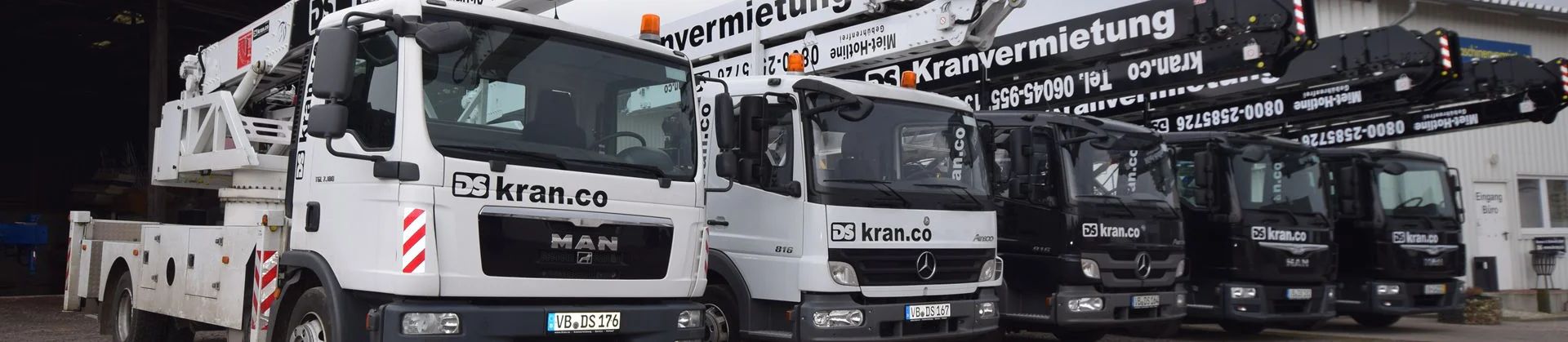 Autokrane Bild von 2 weißen Autokrane und 3 schwarzen Autokranen auf dem Firmengelände dekonal aufgestellt.